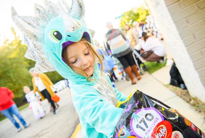 Ellivia Eberle in her dinosaur costume gets some candy from in front of the Alpha Xi Delta sorority Oct. 27, 2021, during IU Safe Halloween along the North Jordan Avenue extension.