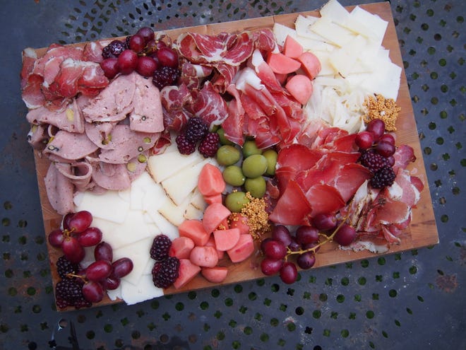 A charcuterie board made by Meredith Leigh, featuring pickled vegetables, fruit and a variety of salumi.