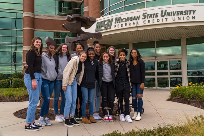 Members of the Michigan State women's basketball player pose for a picture outside of Michigan State University Federal Credit Union. Eligible players have reached name, image and likeness contracts with the credit union for this season.
