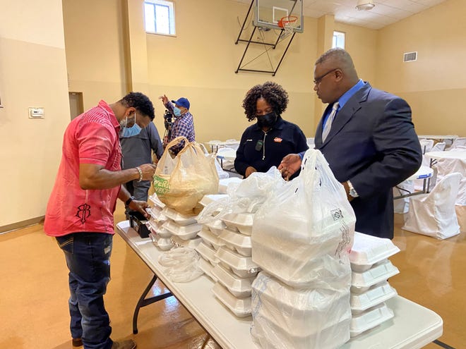 Reginald Cooper (left) and the Rev. Randy Harris (right) get an order of barbeque chicken plate lunches ready for a woman who stopped by Mount Triumph Family Life Center on Friday. The fundraiser was for Donald Wilkinson, a man injured during a police chase in March 2019.