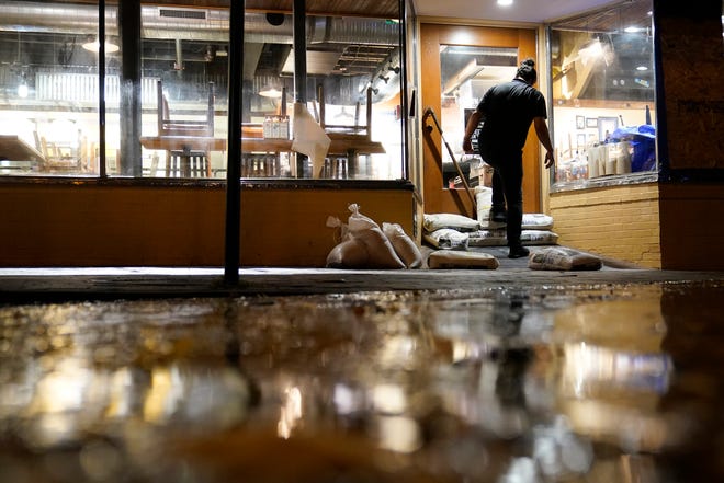 Konrad Karandy puts sandbags in front of a restaurant in downtown Annapolis, Maryland, on Thursday as the water from tidal flooding rises.