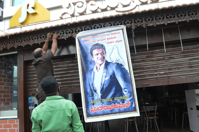 A poster of actor Puneeth Rajkumar is hung outside a hotel with closed shutters after news of the actor's death, in Bengaluru, India, Friday, Oct. 29, 2021.