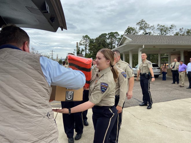 Grant Parish Sheriff's dispatcher Samantha Allen (right) takes her new medical bag and supplies for it from Sheriff Steven McCain (left) after she and 14 of her colleagues graduated from emergency medical responder training.