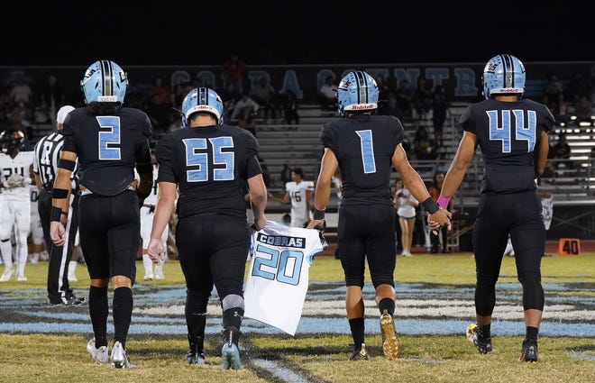 Cactus captains Joseph Lagafuaina (2) Vincent Burgo (55) Will Galvan (1) and Ata Teutupe (44) carry a memorial jersey to the coin toss before their game against Desert Edge Oct, 8, 2021 in Glendale.