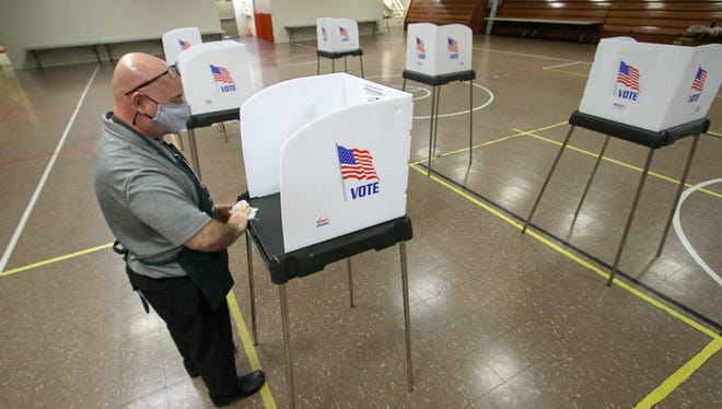 Wayne Wiggins wipes down a voting booth after someone marked their ballot early Tuesday morning, Nov. 2, 2021, at the Adult Recreation Center on West Franklin Boulevard.