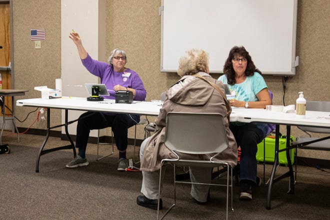 A poll worker at the Ross County Service Center signals for the next voter to come and show their ID so they can vote on Nov. 2, 2021, in Chillicothe, Ohio.  
