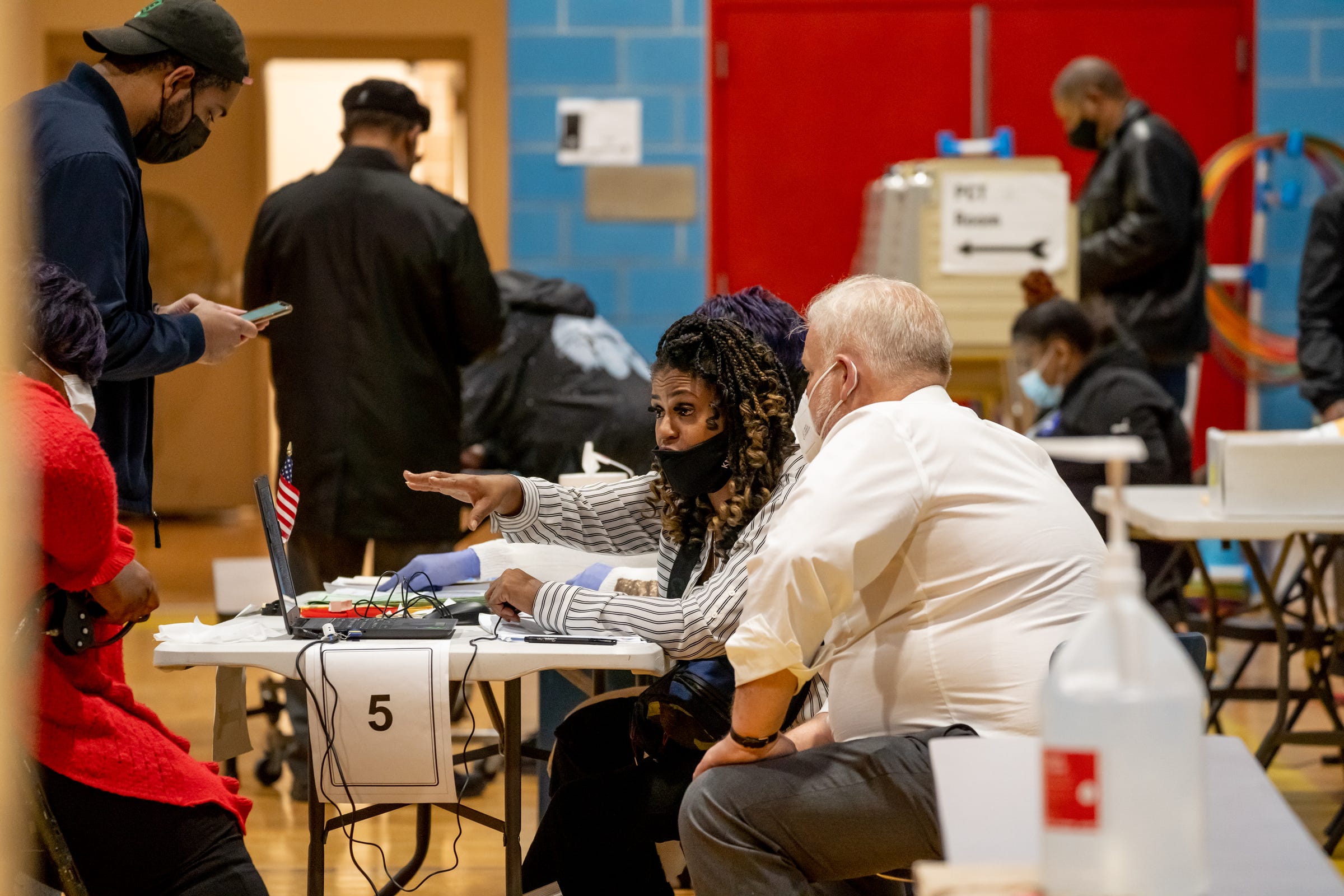 An elections worker helps people prepare to cast their ballots at Carstens Elementary-Middle School in Detroit on November 2, 2021.