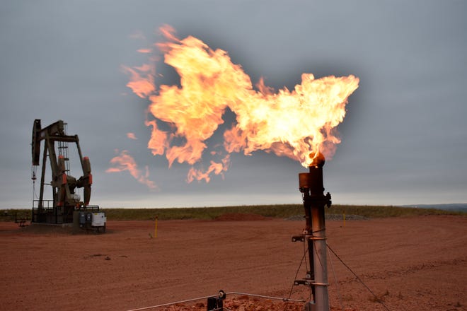 A flare burns natural gas at an oil well on Aug. 26, 2021, in Watford City, N.D. A new federal report released Friday, Oct. 29, 2021, says fossil fuel extraction from federal lands produced more than 1 billion tons of greenhouse gases last year.