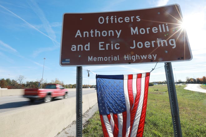The sun peeks around a highway signing memorializing Westerville Police officers Anthony Morelli and Eric Joering stands on I-270. They were killed while responding to a domestic violence call.