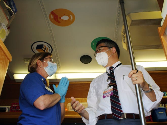 Dr. David Tam, Beebe Healthcare President and CEO, talks to Director of Community Outreach Kim Blanch in a mobile library Beebe converted to a COVID testing clinic.