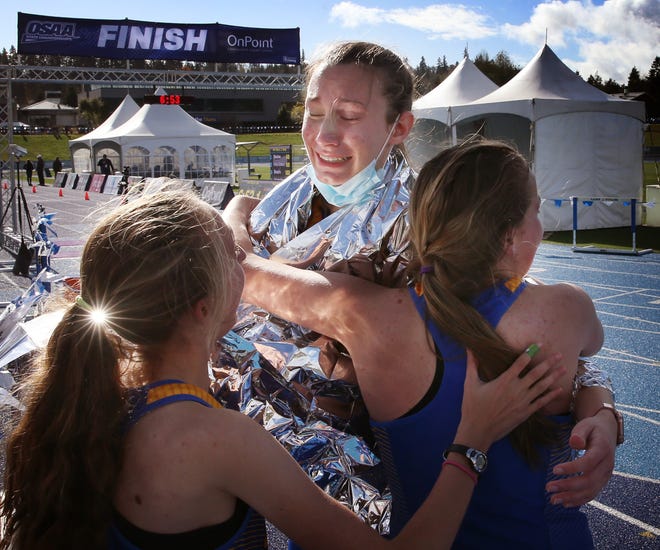 Siuslaw's Rylee Colton, center, celebrates her fifth-place finish and the team's state title at the OSAA 4A girls cross country championship meet at Lane Community College on Saturday.