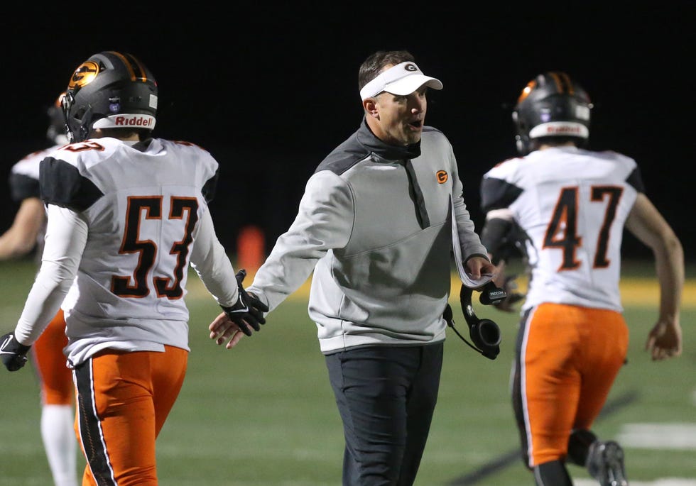 Green head coach Mark Geis greets his players coming off the field during a Nov. 5, 2021 high school football playoff game against Hoover at North Canton Memorial Stadium.