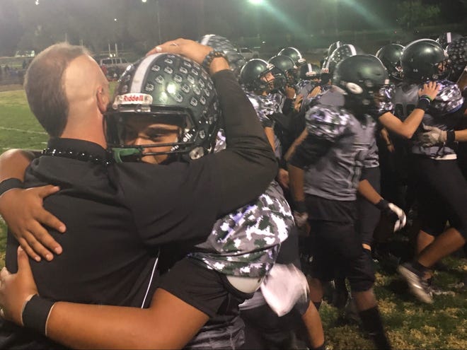 Twentynine Palms head coach TJ Stanford hugs his players after the Wildcats' 33-6 win over AB Miller in the first round of the CIF playoffs on Nov. 5, 2021.