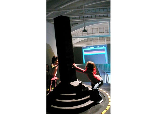 Deux filles actionnent le joystick géant au Centre d'art et de création industrielle LABoral, le 31 mars 2007 dans les Asturies, en Espagne.  La manette de jeu vidéo géante en bois, caoutchouc et acier de Mary Flanagan, professeure au Dartmouth College, a été classée dans le Guinness World Records 2022 en tant que plus grande manette de jeu.