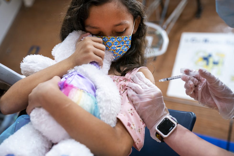 Ximena Tena, 8, receives her first dose of the COVID-19 vaccine while holding onto her stuffed unicorn on Nov. 6, 2021, at Carl Hayden Community High School in Phoenix.