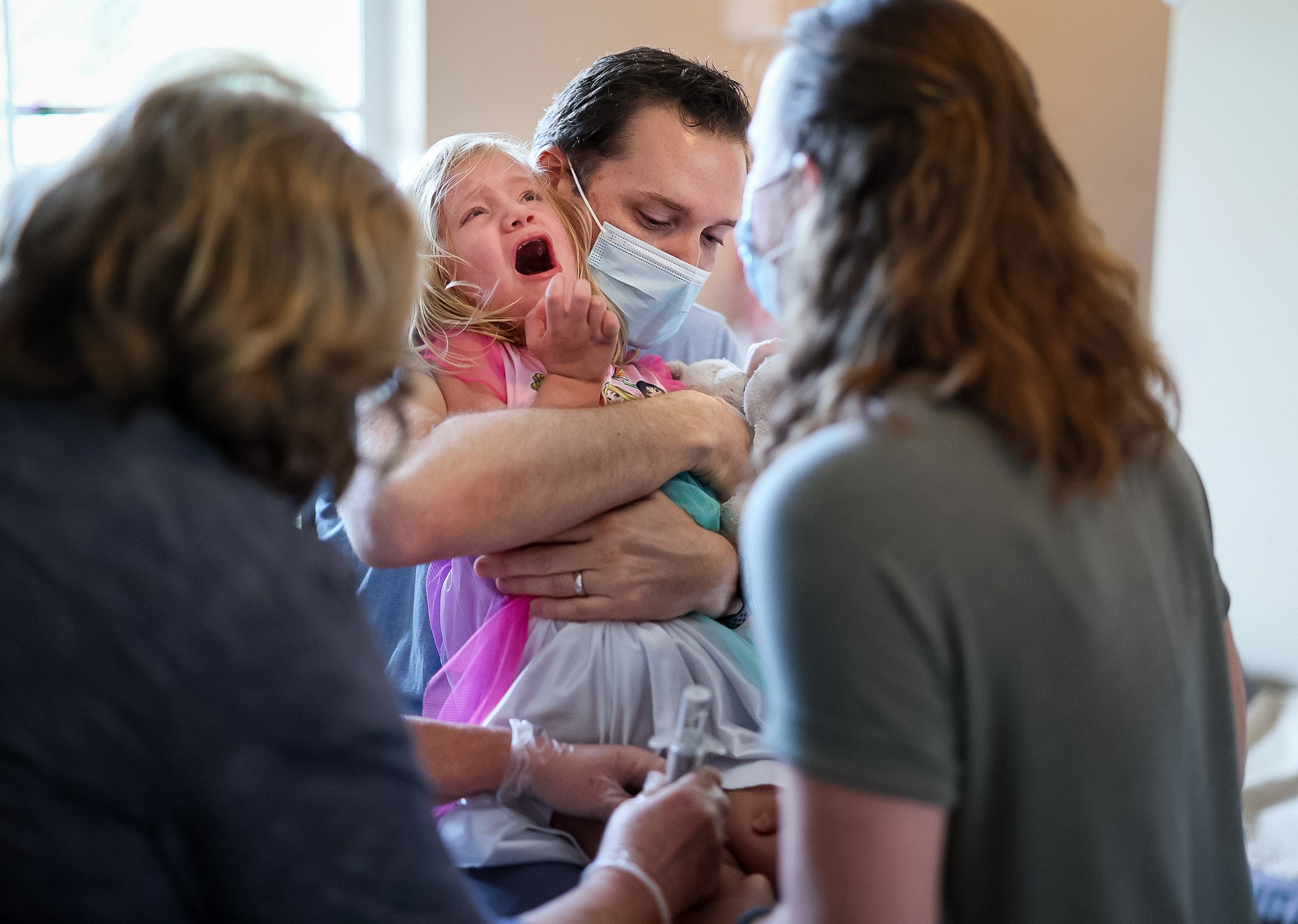 Sarah, right, and Robbie Turner help hold their daughter Emilia, 3, as a visiting nurse administers a shot at their home in Jupiter.