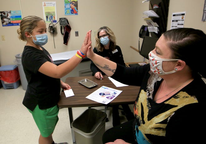 Allee Hill, 9, left, gets a high-five from her mother Amanda Knight after Hill received her COVID vaccine given by Karen Hammersmith, BSN, RN, back, Monday afternoon, Nov 8, 2021.