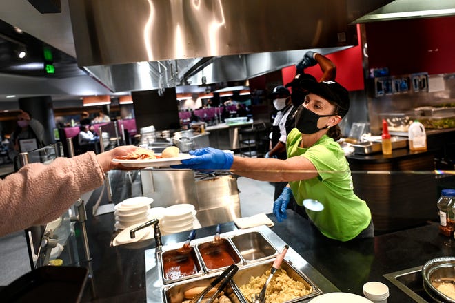 Volunteer Kathi Duncan serves a customer at the Brody Square dining hall on Monday, Nov. 8, 2021, on the MSU campus in East Lansing.