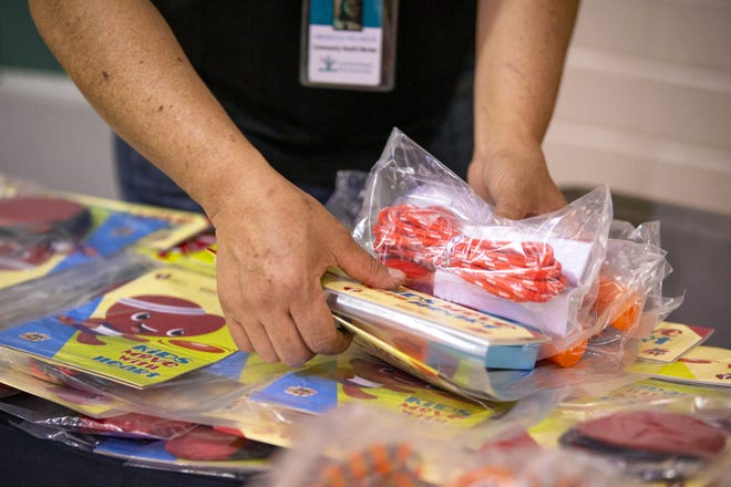 A community health worker with Unlimited Potential gathers a collection of health-driven toys for children at a health fair event at the Webster Community Center in Mesa on Nov. 2, 2021.