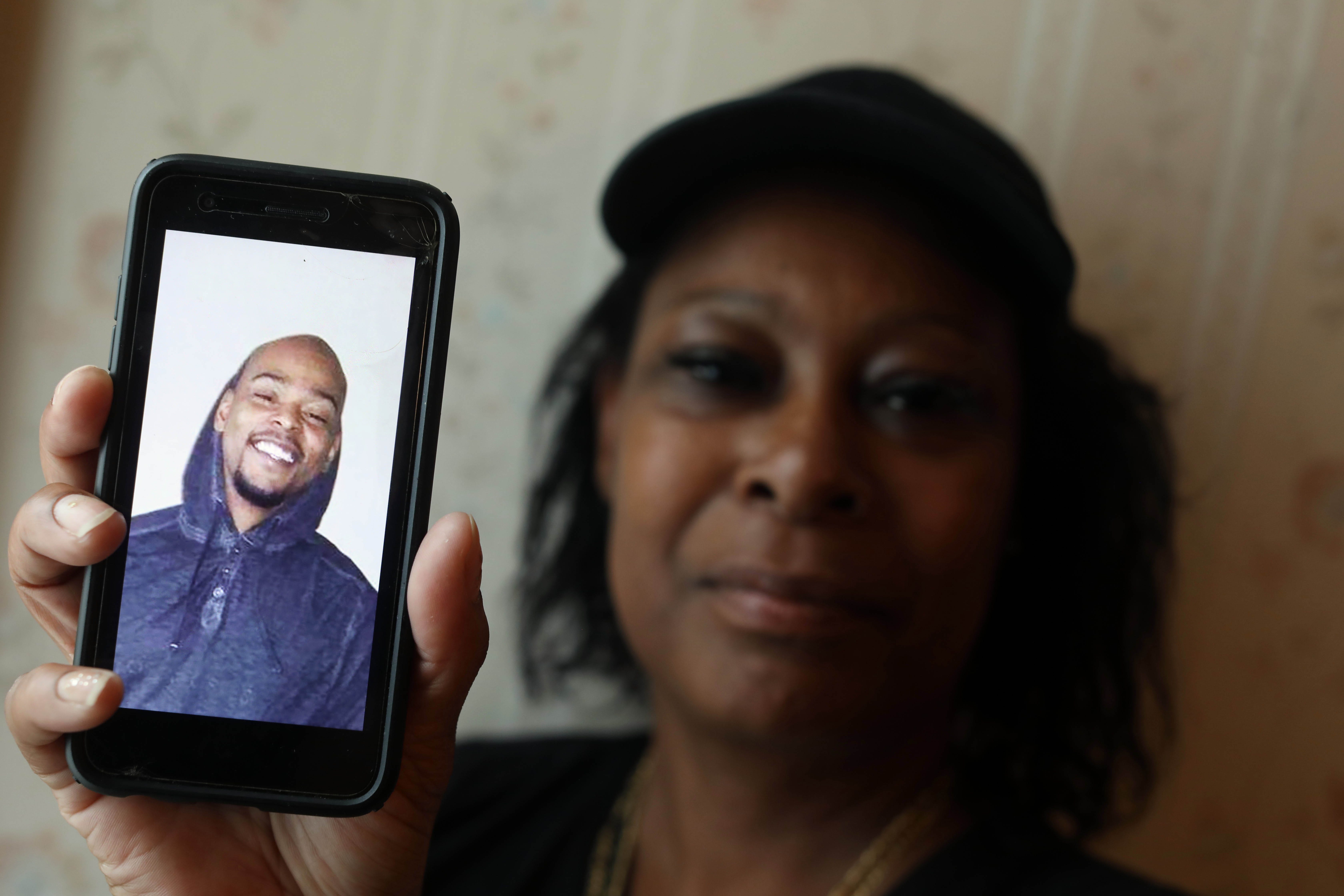 Altovese Williams holding up a phone showing a picture of her son.