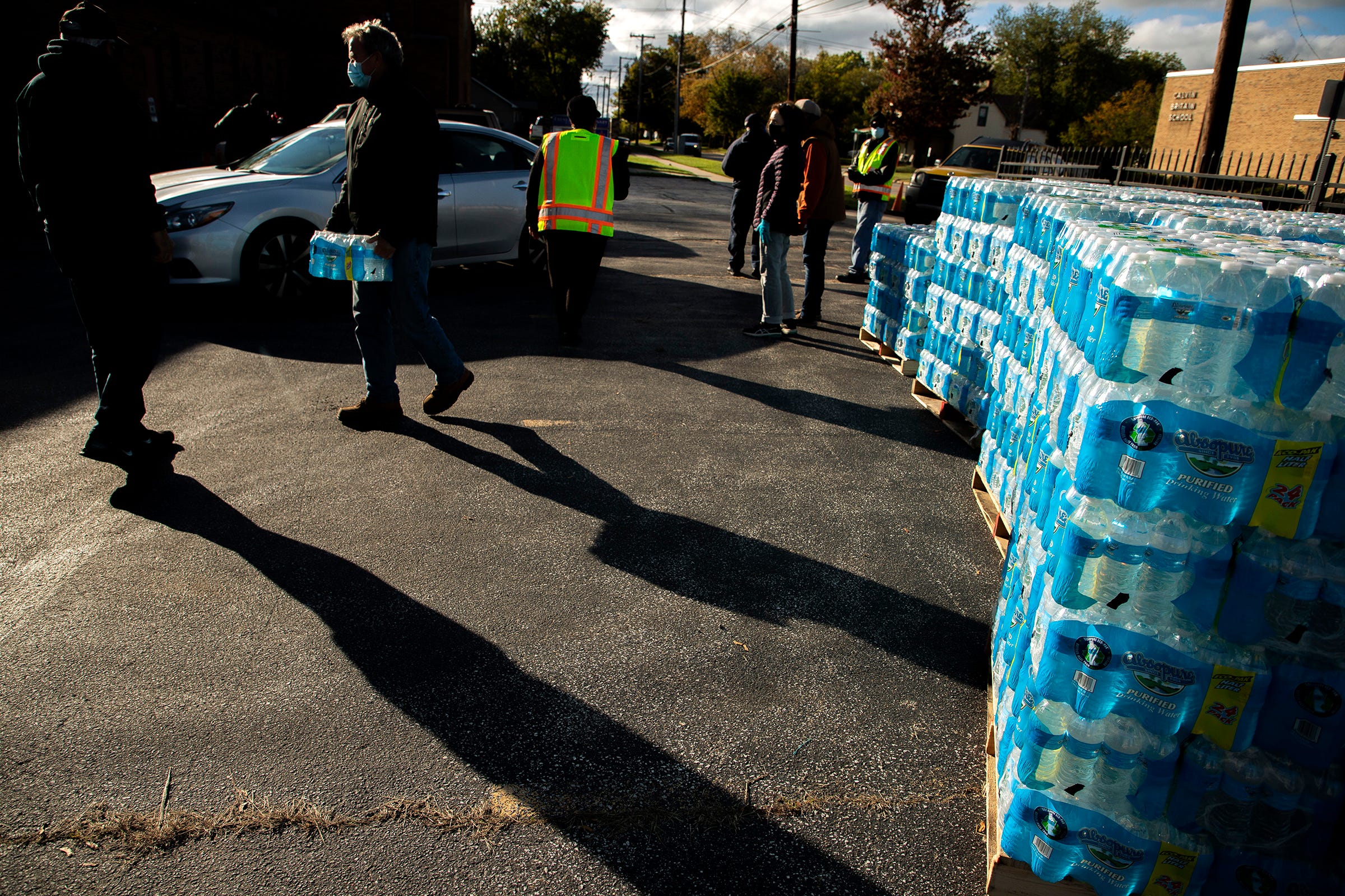 As the sun starts to set, volunteers continue to hand out bottled water to Benton Harbor residents at the Ebenezer Baptist Church on Britain Avenue on October 26, 2021. The church is one of several locations where residents can come to get bottled water to use since their water supply has been found unsafe due to lead levels. Recently, Gov. Whitmer has called for spending $20 million in Benton Harbor to replace nearly 6,000 service lines, most suspected of containing lead, within five years.