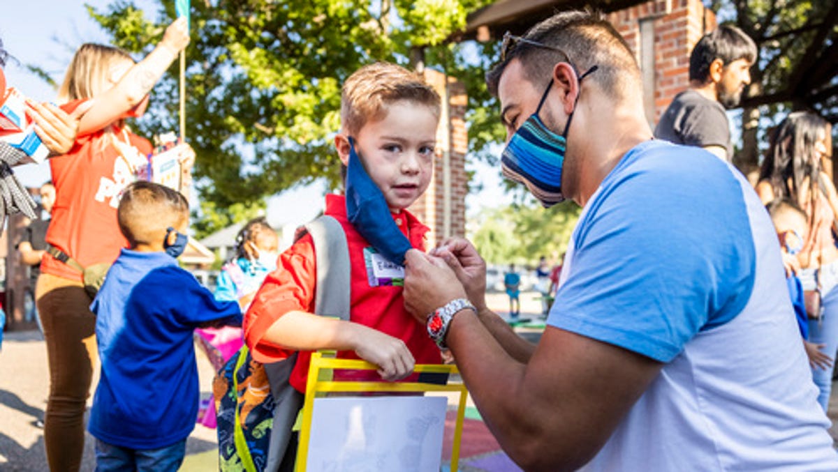 Andres Cardenas adjusts the mask on his son, Garden Place Elementary School kindergartner Edwin Cardenas, 5, as Denver Public Schools welcomed students and teachers back to classrooms on Aug. 23, 2021 for the first day of the academic year.