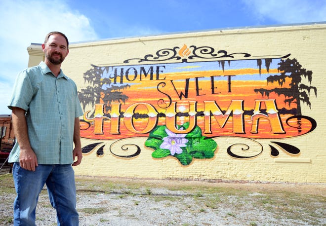 Terrebonne artist Hans Geist poses for a photo Wednesday with his most recent mural, Home Sweet Houma, in the background. The mural was started and completed in early November.