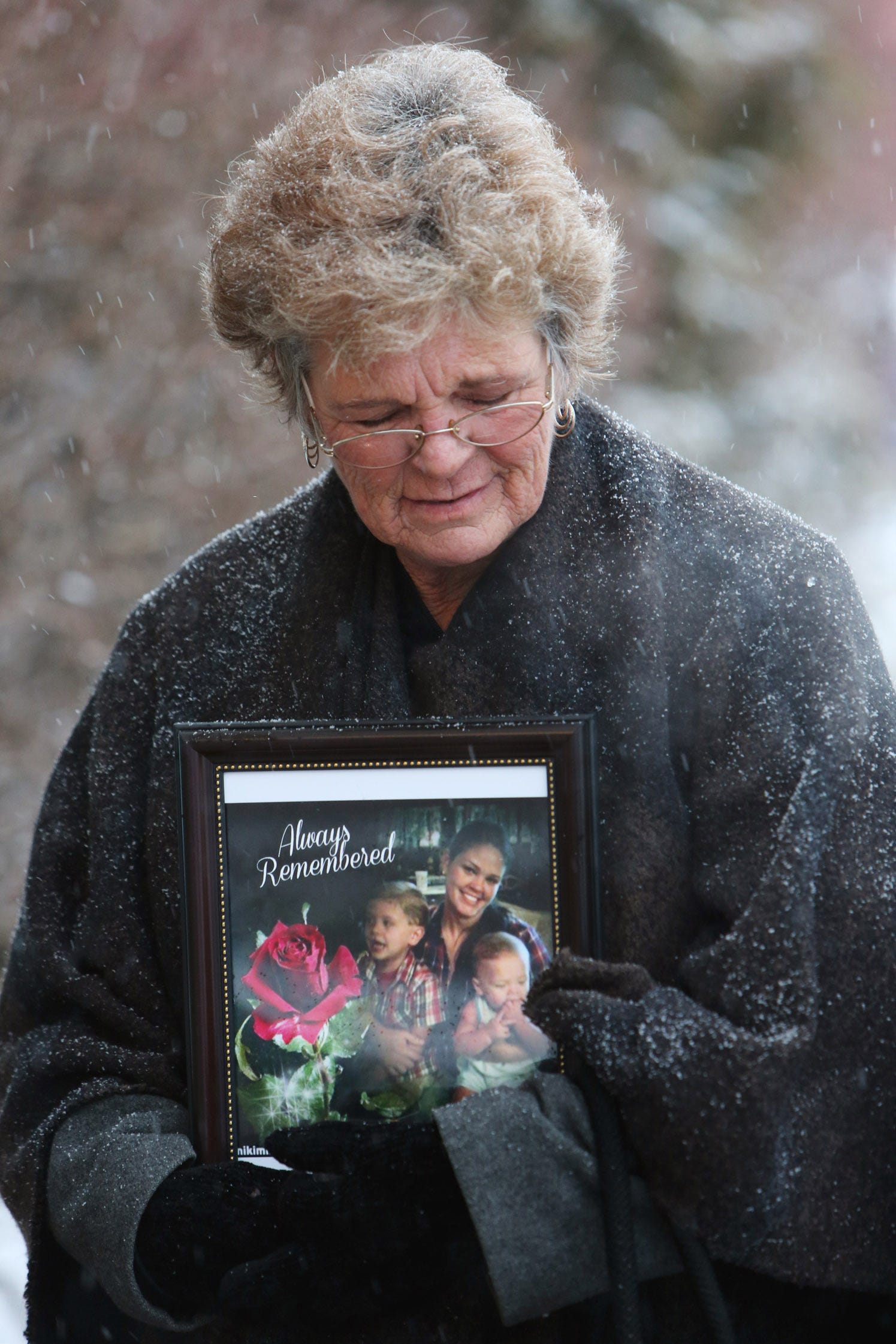 Gina Colbert holding a framed photo of her daughter that says 