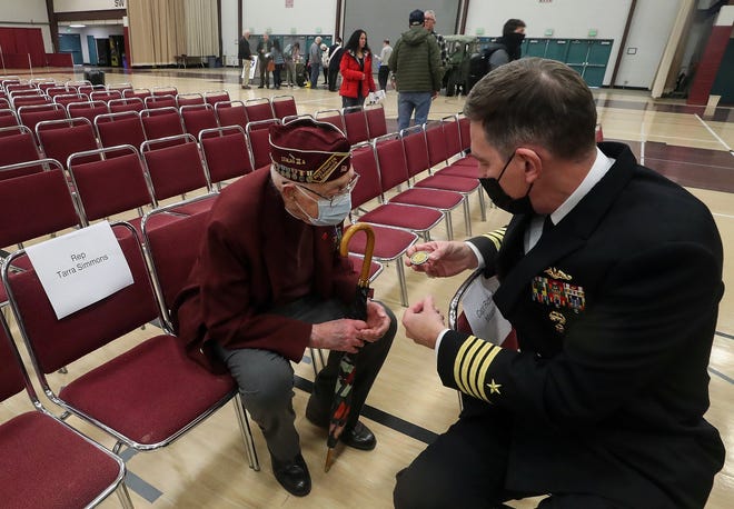 Capt. Richard Massie, commanding officer of Naval Base Kitsap (right) gifts a challenge coin to World War II veteran and Prison Of War Bob Meyer, of Belfair, as the two chat at the Honoring All Who Served Veterans Day event at the Kitsap County Fairgrounds on Thursday.