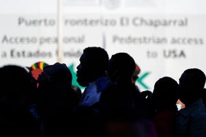 Pencari suaka yang menunggu di Meksiko mengantre di perbatasan untuk menerima berita tentang perubahan kebijakan di Tijuana, Meksiko.