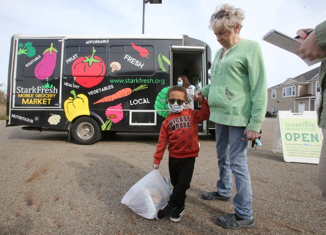 Blazon Houston holds the hand of his godmother, Deborah Bigrigg, after receiving items from StarkFresh's mobile market Thursday at the Wellness Village at Midway in Canton.