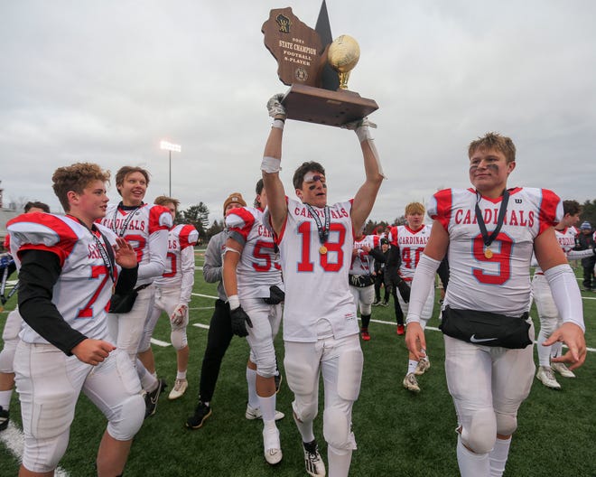 Newman Catholic's Josh Klement (18) holds up the state championship trophy after the WIAA 8-player state championship football game against Luck on Nov. 13 at South Wood County Stadium in Wisconsin Rapids.