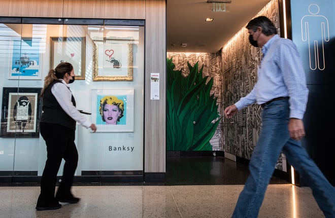 Travelers and staff on Monday at Austin-Bergstrom International Airport stroll past the newly installed gallery of Banksy prints in the nine-gate extension of the Barbara Jordan Terminal. The prints are among several artworks featured throughout the terminal.