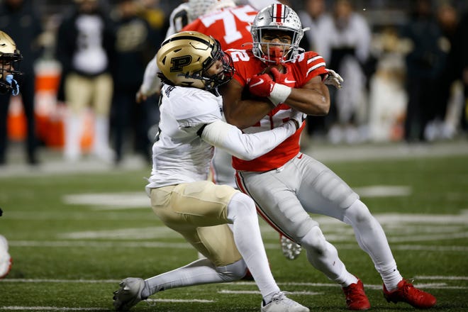 Ohio State running back TreVeyon Henderson, right, is tackled by Purdue defensive back Marvin Grant during the second half of an NCAA college football game Saturday, Nov. 13, 2021, in Columbus, Ohio. (AP Photo/Jay LaPrete)