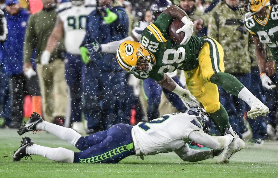 Green Bay Packers running back AJ Dillon (28) breaks a tackle by Seattle Seahawks cornerback D.J. Reed.