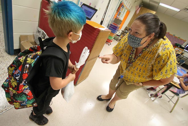 Kindergarten teacher Tiffany Jattan greets 5-year-old Briar Tilley as he enters his classroom on the first day of school at Woodhill Elementary School in Gastonia early Monday morning, Aug. 23, 2021. Masks will no longer be required of students or teachers after Thanksgiving.