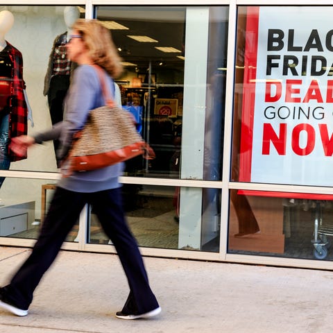 Customers walk past Black Friday sale signs at the