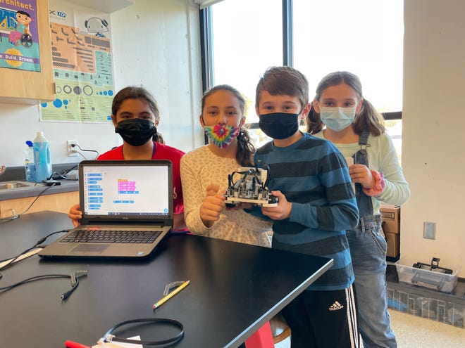 Fifth-graders Georgia Condakes, Tessa Vicente, Noah Gosselin and Daniella Quagenti show the robot they built and the program they are working on to have it complete missions.