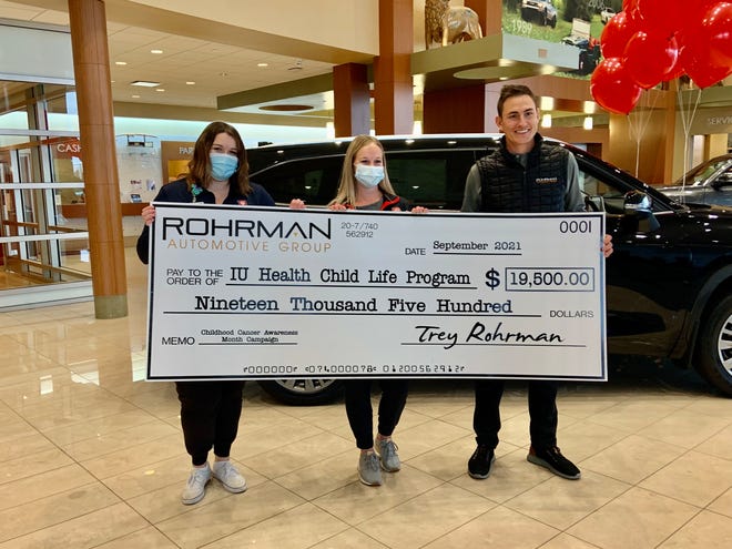 IU Health Arnett Child Life Specialists Olivia Rauschenbach (left) and Mollie Lane (center), and Trey Rohrman, director of Indiana Operations at Rohrman Automotive Group holding the $19,500 check donation to the Child Life program.