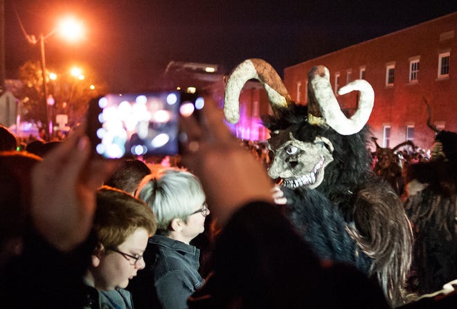 A Krampus intimidates a "naughty" participant as another takes a video on her phone during the 2017 Krampus Rampage in downtown Bloomington.