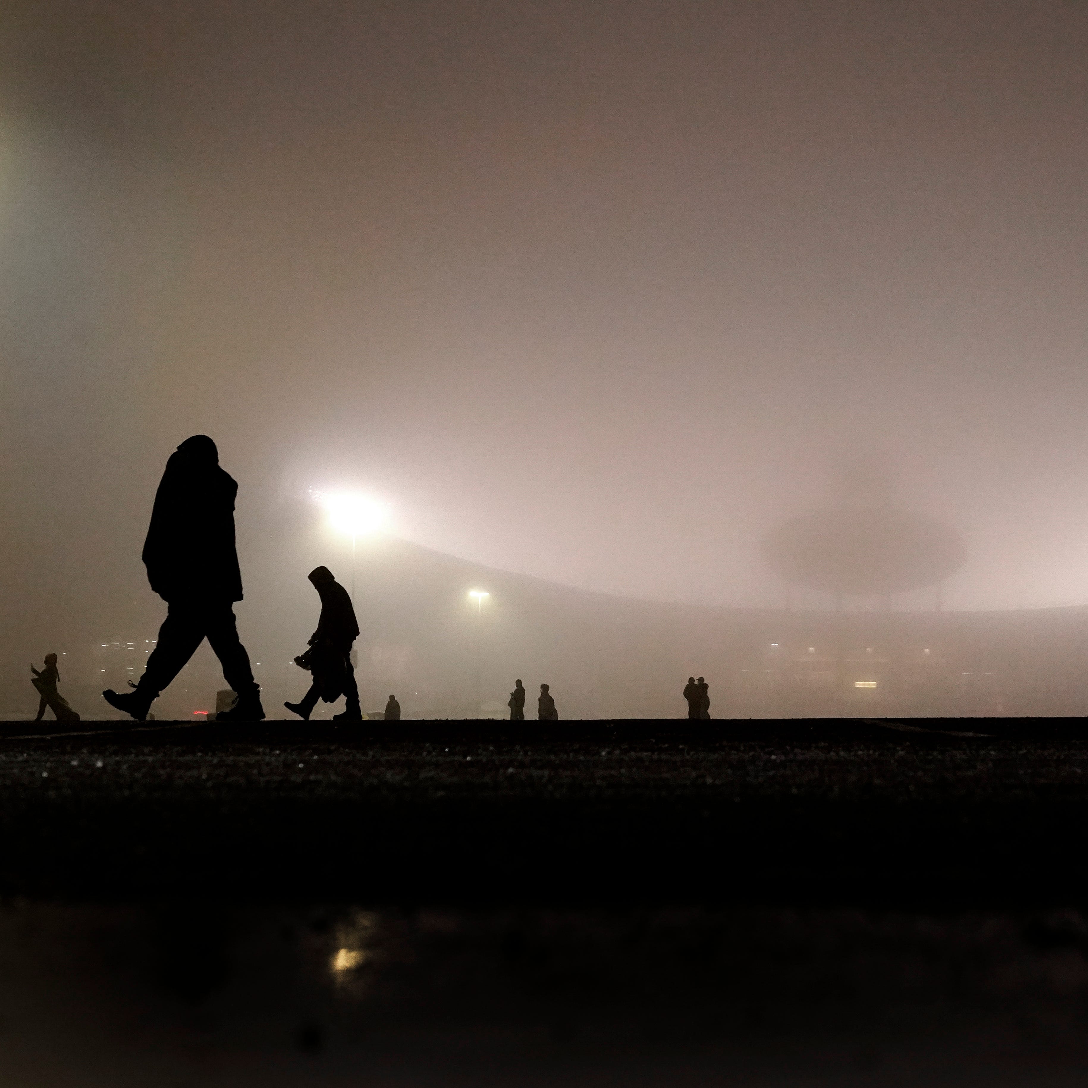 January 3, 2021:  People are shrouded in fog as they clean trash from a parking lot at Arrowhead Stadium after an NFL football game between the Los Angeles Chargers and the Kansas City Chiefs, in Kansas City, Mo.