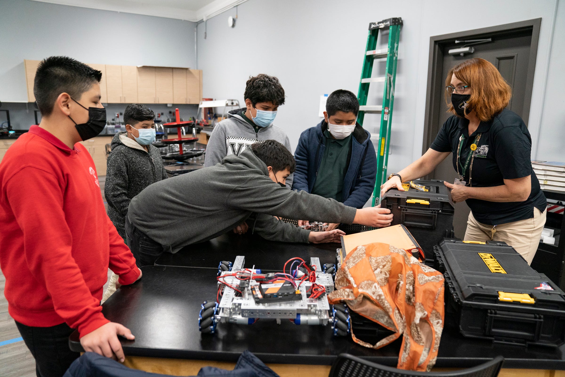 Students from Neinas Dual Language Learning Academy from left, Anthony Sanchez, 13, Francisco Brabo, 12, Anthony Florentin, 12, Owen Reyes, 12, and Daniel Roblero, 12, join robotics coach Ann McGowan at Cristo Rey High School as they participate in learning robotics on Nov. 18, 2021 at Cristo Rey High School in Detroit.