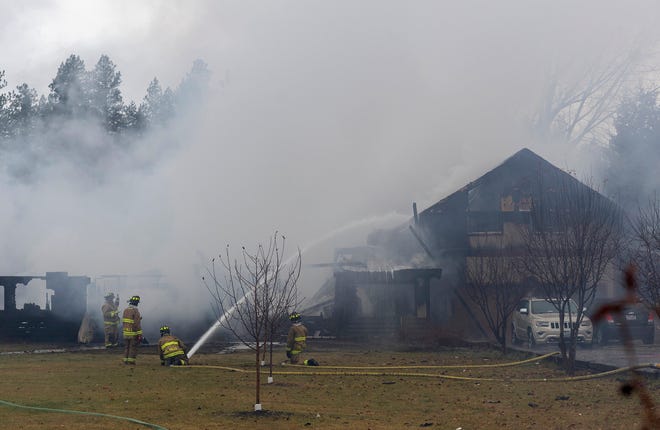 Columbia Falls firefighters work to extinguish a massive house fire on Nov. 14, 2021, south of Whitefish, Mont. Authorities say two people were killed in the blaze.