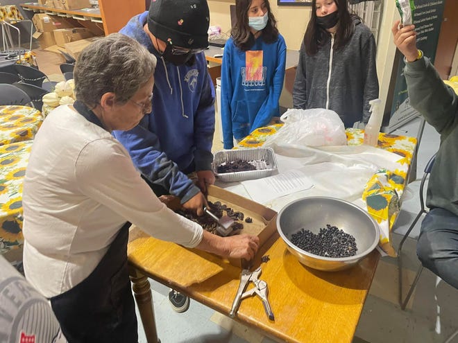 Indigenous children in South Dakota learn how to make wasna, a traditional Plains Indian dish consisting of berries.  In this step, they are processing chokecherries