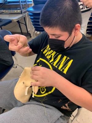 A child at the Cheyenne River Sioux reserve in South Dakota stitches a moccasin together