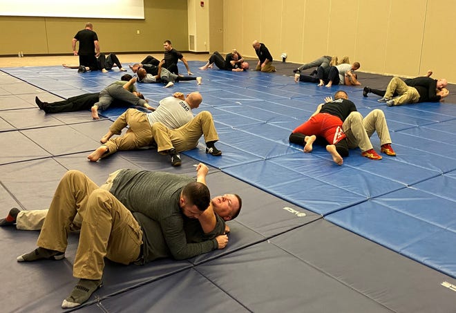 Kansas Law Enforcement Centers students in the Gracie University jiu-jitsu training program practice defending and escape the side mount, which involves creating space and pulling a leg through.
