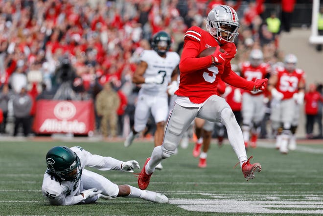 Nov 20, 2021; Columbus, Ohio, USA; Ohio State Buckeyes wide receiver Garrett Wilson (5) leaps over Michigan State Spartans safety Angelo Grose (15) in the first half at Ohio Stadium.
