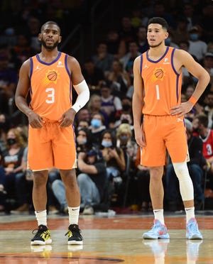 Phoenix Suns guard Devin Booker and Phoenix Suns guard Chris Paul  look on against the Dallas Mavericks during the first half at Footprint Center.