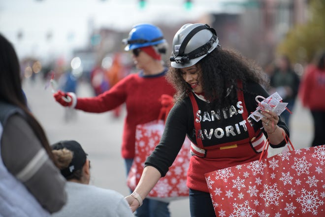 Rachel Terry from Strataca Salt Mine and Museum hands out candy canes affixed with flyers about upcoming events at the museum during the annual Hutchinson Christmas Parade on Saturday, Nov. 20, 2021, in downtown Hutchinson.