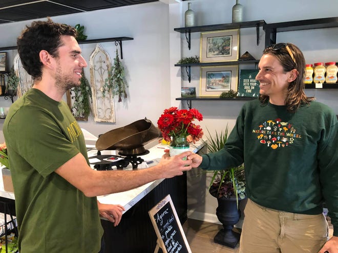 Cedar Wood of Charles City presents Agoria Market founder Joey Puletti with Zinnias to welcome the new business to Petersburg.